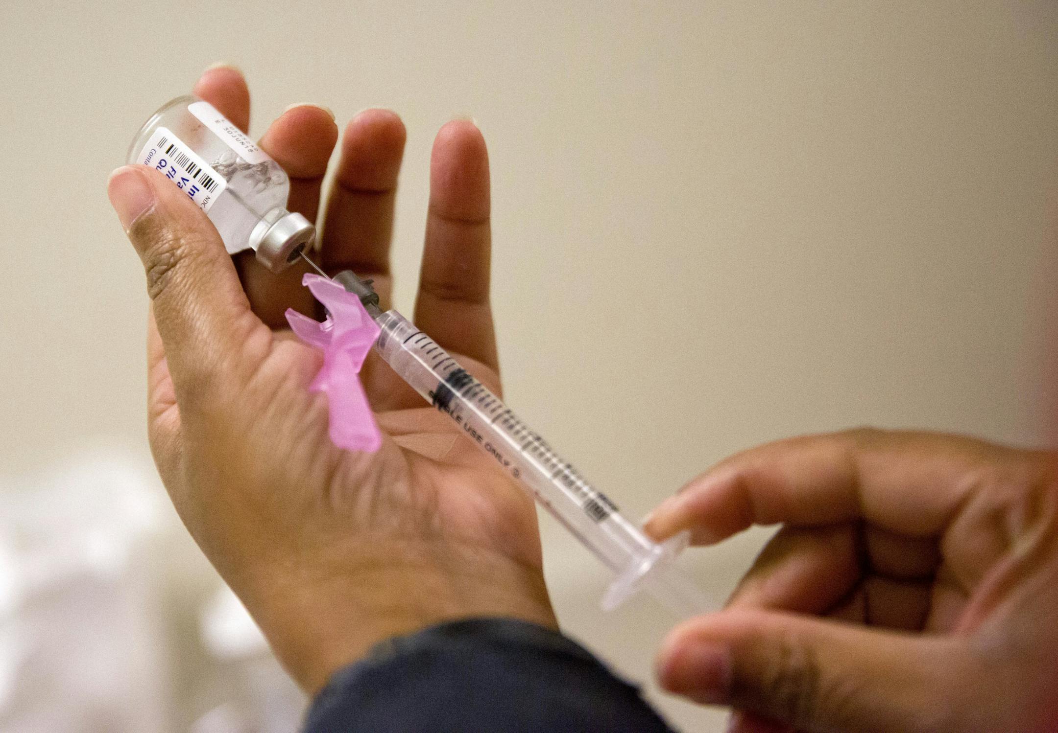 FILE - In this Feb. 7, 2018 file photo, a nurse prepares a flu shot at the Salvation Army in Atlanta. According to the CDC, flu costs the nation about $7 billion a year in sick days and lost productivity among working-age adults. That&#x2019;s not to mention the heavy toll of hospitalizations and deaths that occur mainly among people 65 and older. (AP Photo/David Goldman)