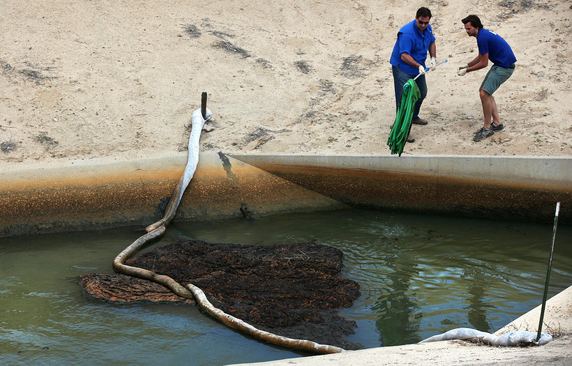 Scott Smith, chief scientist at Water Defense, left, and assistant Skye Wallin, right, retrieve foam sponges which were deployed to absorb test water from a canal operated by the Cawelo Water District March 16, 2015 near Bakersfield, Calif. The canal moves oil produced water mixed with fresh water for use by Kern County agriculture. (Brian van der Brug/Los Angeles Times/TNS)