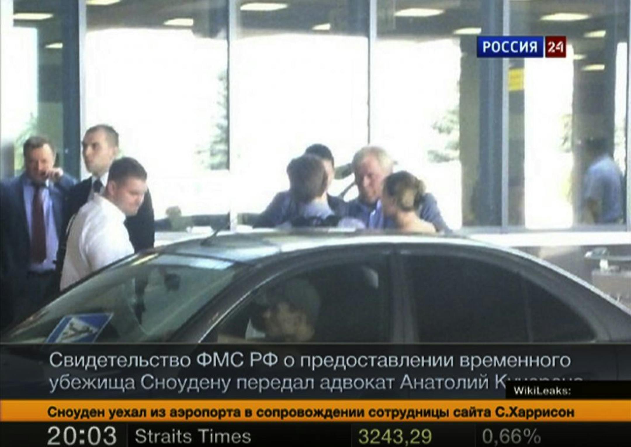 In this still image taken on Thursday, Aug. 1, 2013 and released by Russia24 TV channel, shows Russian lawyer Anatoly Kucherena, second right in the center, and National Security Agency leaker Edward Snowden, center back to a camera, as Snowden leaves Sheremetyevo airport outside Moscow, Russia, on Thursday, Aug. 1, 2013. Snowden has received asylum in Russia for one year and left the transit zone of Moscow's airport, his lawyer said Thursday. Kucherena said that Snowden's whereabouts will be ke