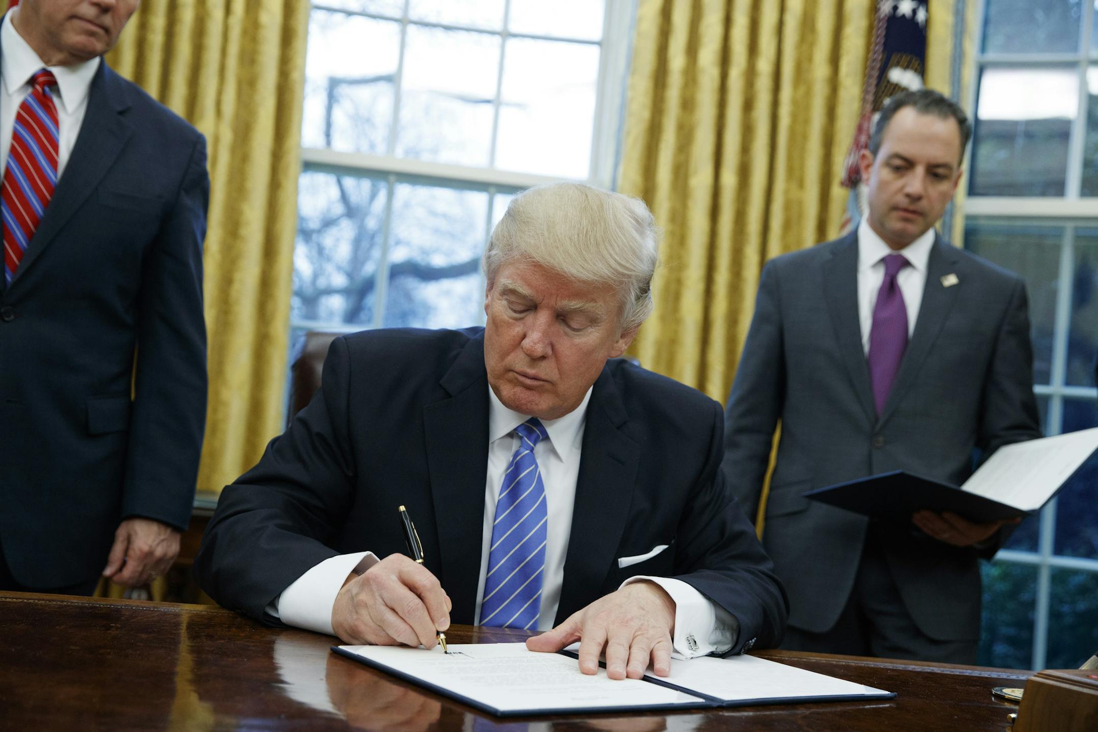 FILE - In this Monday, Jan. 23, 2017, file photo, President Donald Trump signs an executive order to withdraw the U.S. from the 12-nation Trans-Pacific Partnership trade pact agreed to under the Obama administration in the Oval Office of the White House in Washington. With his rejection of an Asian trade pact, Trump has started tackling policy changes that could inadvertently give China room to assert itself as a regional leader and worsen strains over the South China Sea and Taiwan. (AP Photo/E