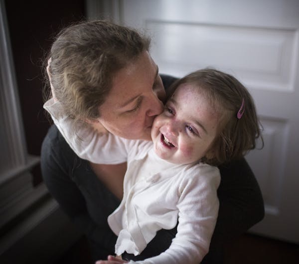 Gabriella McCann gives daughter Elisa a gentle smooch. A rare skin condition leaves the girl in chronic pain.