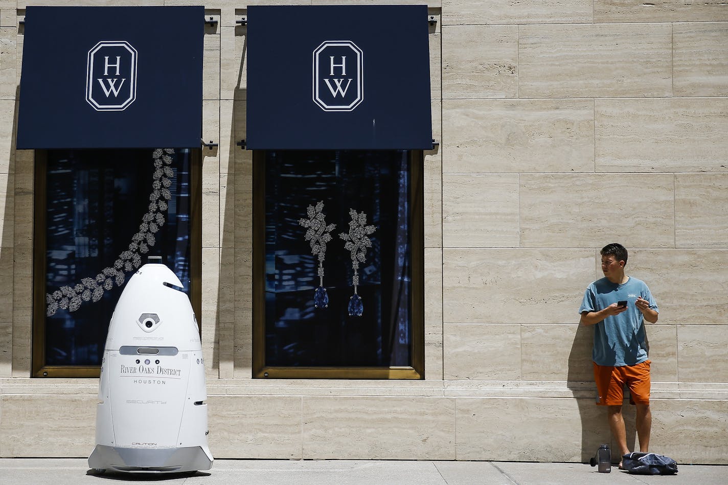 FILE - In this Friday, Aug. 18, 2017, file photo, a new security robot, nicknamed ROD2, drives toward Daniel Webb as it patrols the sidewalks and parking garage at River Oaks District in Houston. The robot recently became the latest addition to a patrol team eager to experiment with fast-evolving technology. According to a survey by the Pew Research Center, three-quarters of Americans say it is at least "somewhat realistic" that robots and computers will eventually perform most of the jobs curre