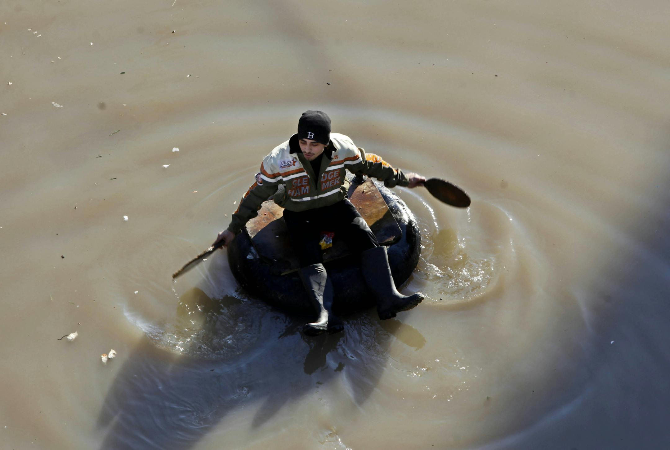 A Palestinian man rides a tire as a boat looking for residents who need food supplies after their homes were flooded from heavy rain water in Gaza City, Sunday, Dec. 15, 2013. Rescue workers evacuated more than 5,000 Gaza Strip residents from homes flooded by four days of heavy rain, using fishing boats and heavy construction equipment to pluck some of those trapped from upper floors, an official said on Saturday. (AP Photo/Adel Hana)