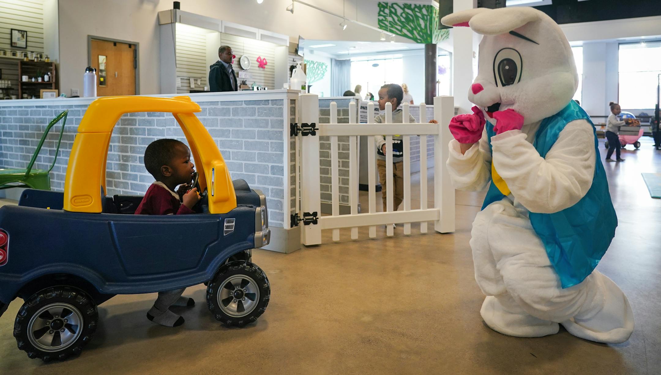 The Easter Bunny, right, greets Asher Rwema, 2, whose mother said enjoys riding the cars at MiniSota Cafe in Maple Grove. "He'll be in that car the whole day," she said.