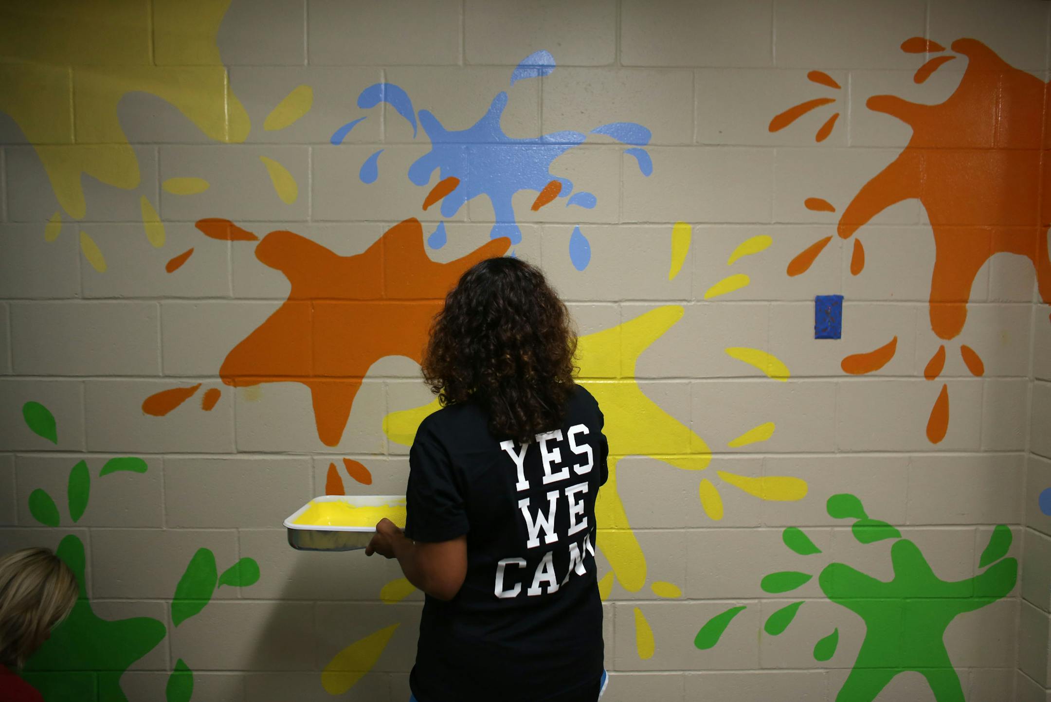 Angi Stoltzmann, 5th grade math teacher, put on a second coat of paint on the artful splashes on one of the hallway walls. ] (KYNDELL HARKNESS/STAR TRIBUNE) kyndell.harkness@startribune.com During a day of "beautification" at Northport Elementary School in Brooklyn Park, Min., Tuesday, August, 19, 2014.