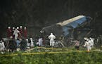 Rescue teams search through the wreckage site of a Boeing 737 that plummeted into a cassava field with more than 100 passengers on board, in Havana, C