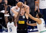 Anthony Edwards and Karl-Anthony Towns of the Wolves defend the Nuggets' Nikola Jokic during a playoff game May 19 in Denver.