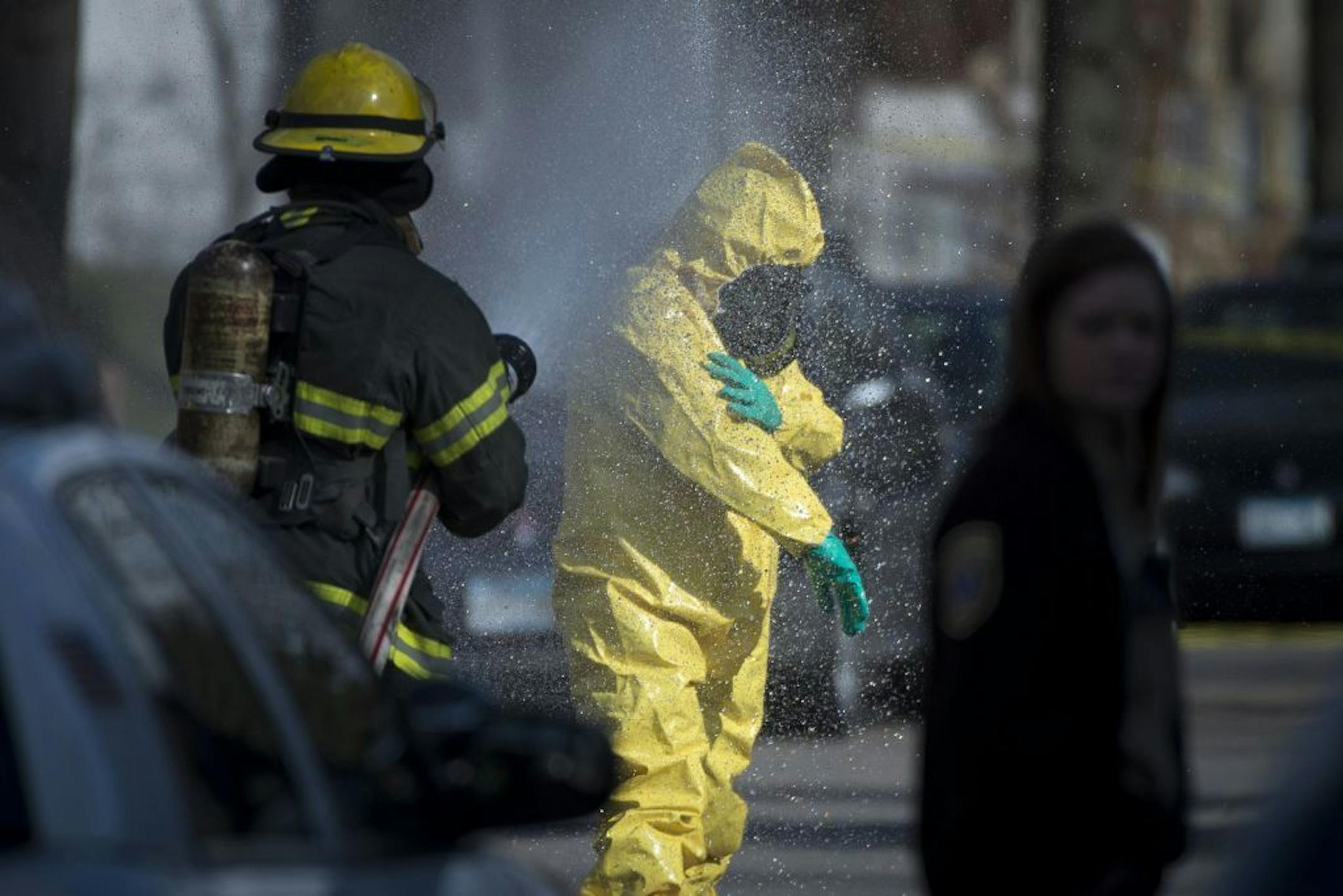 A hazardous material worker is hosed down by a member of the Minneapolis Fire Department after leaving a residence in the Marcy Holmes neighborhood of Minneapolis on the 500 block of 6th Street Southeast on Friday, April 10, 2015.