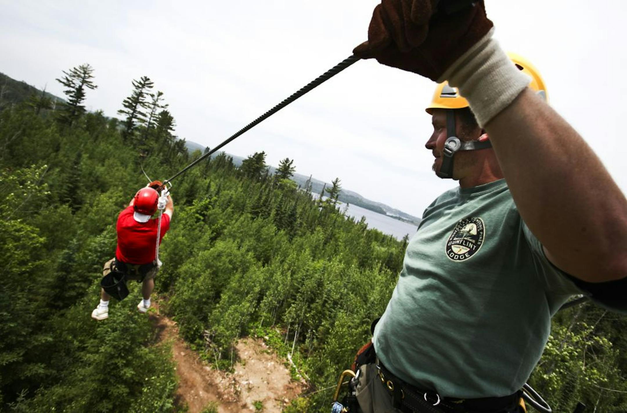 Under the watchful eye of Jason Merrill, safety director for Up North: Minnesota Towering Pine Canopy Tours, right, Star Tribune reporter Curt Brown zips to platform five, about 800 feet away,