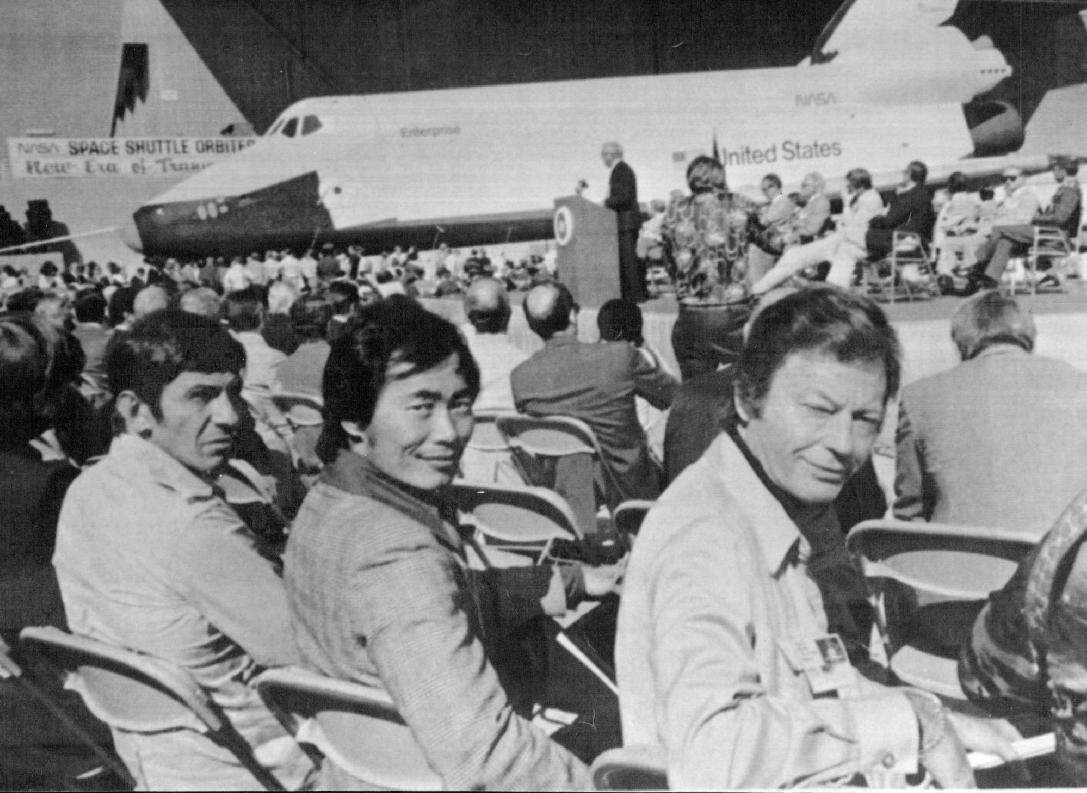 September 17, 1976 THE ENTERPRISE AND AN ENTERPRISE CREW--America's Space Shuttle is shown in the background Friday after it's first showing in Palmdale, Calif. In the foreground is the crew of the television series Star Trek, who's ship was also named Enterprise. From left: Leonard Nimoy who portrayed Dr. Spock; George Takai who was Mr. Sulu; and DeForest Kelly who was Dr. McCoy. September 18, 1976 AP Wirephoto; Minneapolis Star Tribune