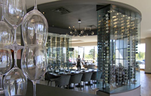 At sunny, airy Lela in Bloomington, the wide-open dining room is divided by sculptural stacks of wine glasses and by glass-walled wine racks.