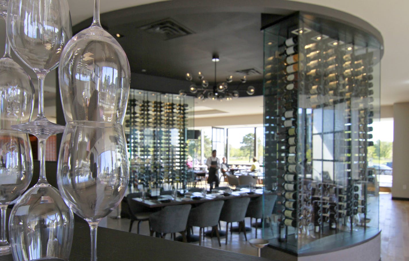 At sunny, airy Lela in Bloomington, the wide-open dining room is divided by sculptural stacks of wine glasses and by glass-walled wine racks.