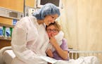 Reagan Lennes, 6, is consoled by her mother Lisa Lennes before heading into surgery, a canaloplasty and tracheostomy scar revision surgery, at Hennepi