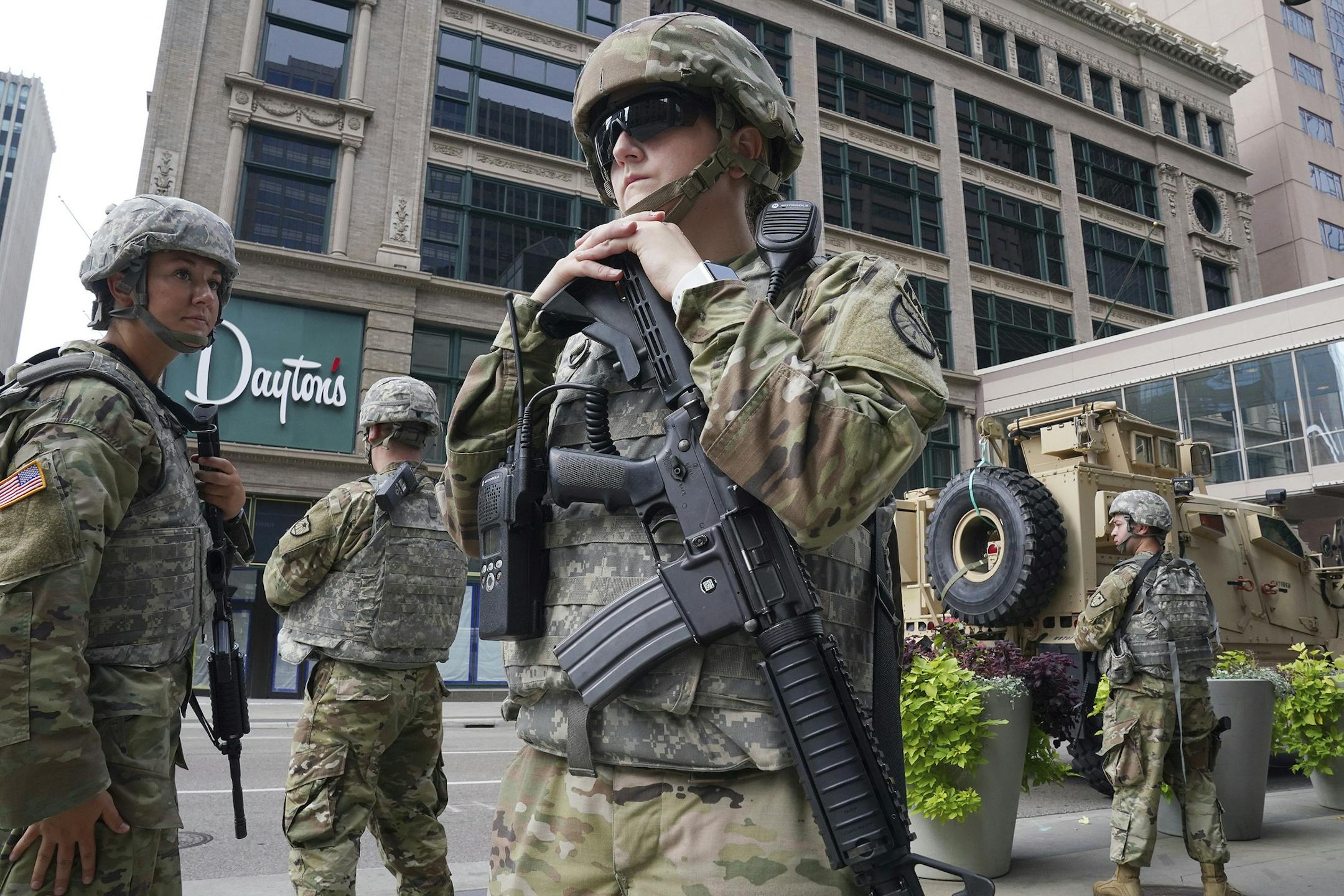 Members of the Minnesota National Guard stand at the intersection of South 7th Street and Nicollet Mall, Thursday, Aug. 27, 2020, in Minneapolis, as community members and business owners cleaned up the damaged that was caused by a group of looters Wednesday night after the suicide of a homicide suspect on the Mall ignited rioting. (Anthony Souffle/Star Tribune via AP)