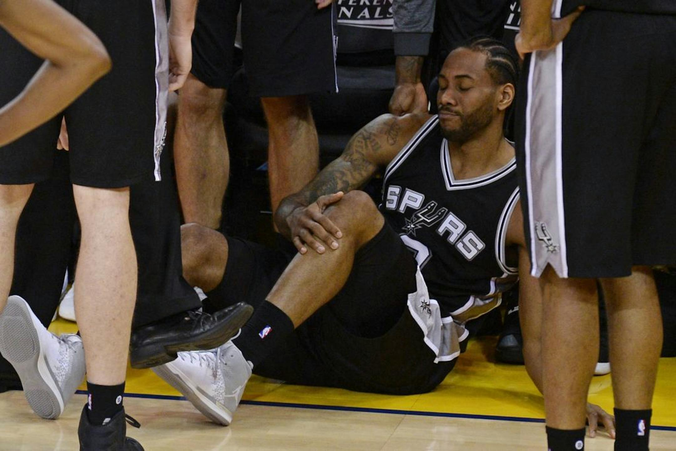 San Antonio Spurs' Kawhi Leonard (2) grabs his leg after suffering an injury while playing against the Golden State Warriors during the third quarter of Game 1 of the NBA Western Conference Finals on Sunday, May 14, 2017 at Oracle Arena in Oakland, Calif. The Golden State Warriors defeated the San Antonio Spurs 113-111.