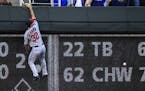 Minnesota Twins left fielder Logan Schafer climbs the wall after a fly ball hit by Kansas City Royals' Paulo Orlando during the second inning of a bas