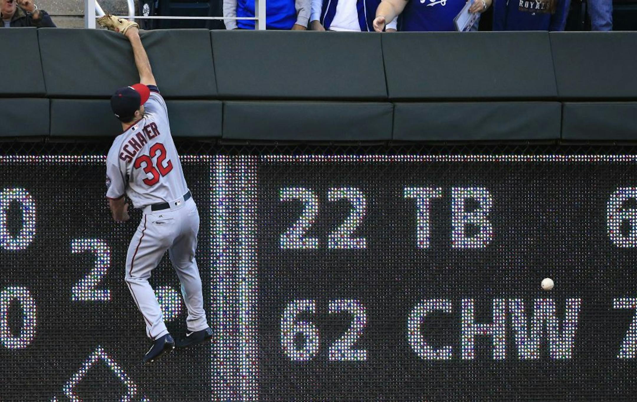 Minnesota Twins left fielder Logan Schafer climbs the wall after a fly ball hit by Kansas City Royals' Paulo Orlando during the second inning of a baseball game at Kauffman Stadium in Kansas City, Mo., Thursday, Sept. 29, 2016. Orlando doubled on the play.