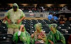 From left, Mike and Jannetta Spahn, of Plymouth, and Michele and Erin Horan, of St. Paul, put on their ponchos during a rain delay before the start of