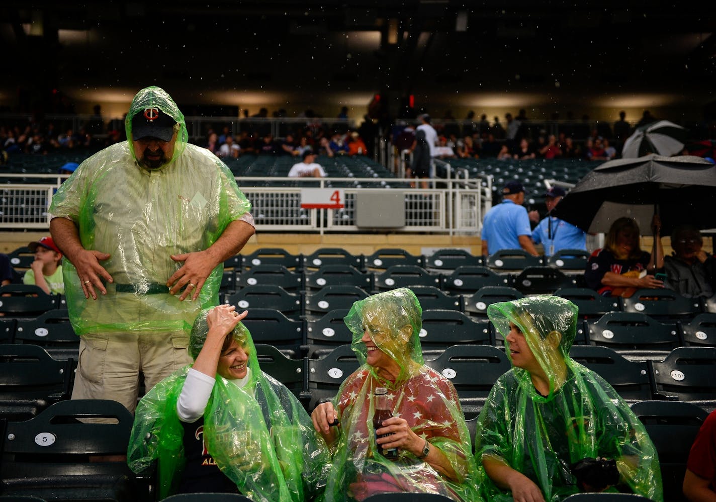 From left, Mike and Jannetta Spahn, of Plymouth, and Michele and Erin Horan, of St. Paul, put on their ponchos during a rain delay before the start of Wednesday night's game.