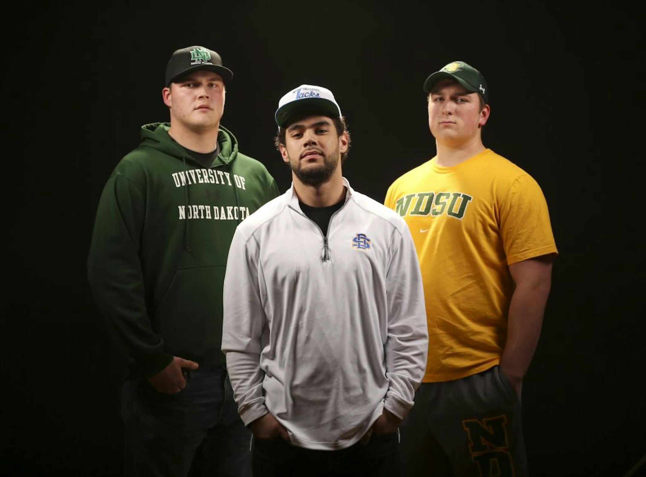 The big Dakota Universities – UND, NDSU, SDSU, USD – are luring the best football players from Minnesota high schools in greater numbers than before. Zack Ziemer (North Dakota State University), Mikias Alipate (South Dakota State University), and A.J. Stockwell (North Dakota), from left, all will sign Letters of Intent on Wednesday.