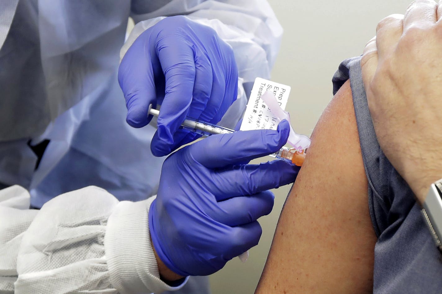 Neal Browning receives a shot in the first-stage study of a potential vaccine for COVID-19, the disease caused by the new coronavirus, Monday, March 16, 2020, at the Kaiser Permanente Washington Health Research Institute in Seattle. Browning is the second patient to receive the shot in the study. (AP Photo/Ted S. Warren)