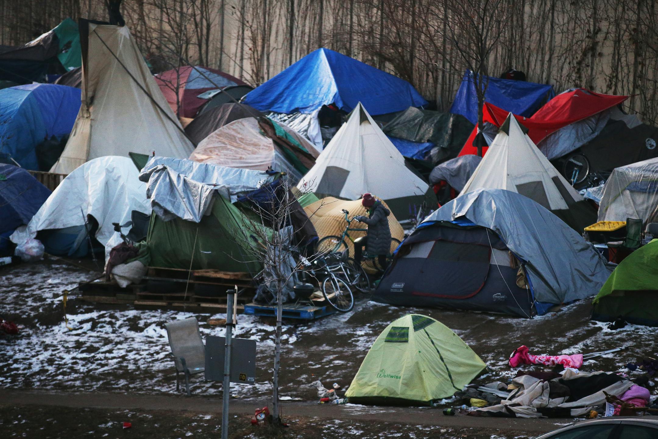 At dusk, a resident of the Hiawatha homeless encampment uses a flashlight to light the dark as she put away her bike before heading into her tent for the night Wednesday, Nov. 14, 2018, in Minneapolis, MN.] DAVID JOLES • david.joles@startribune.com Hiawatha homeless encampment