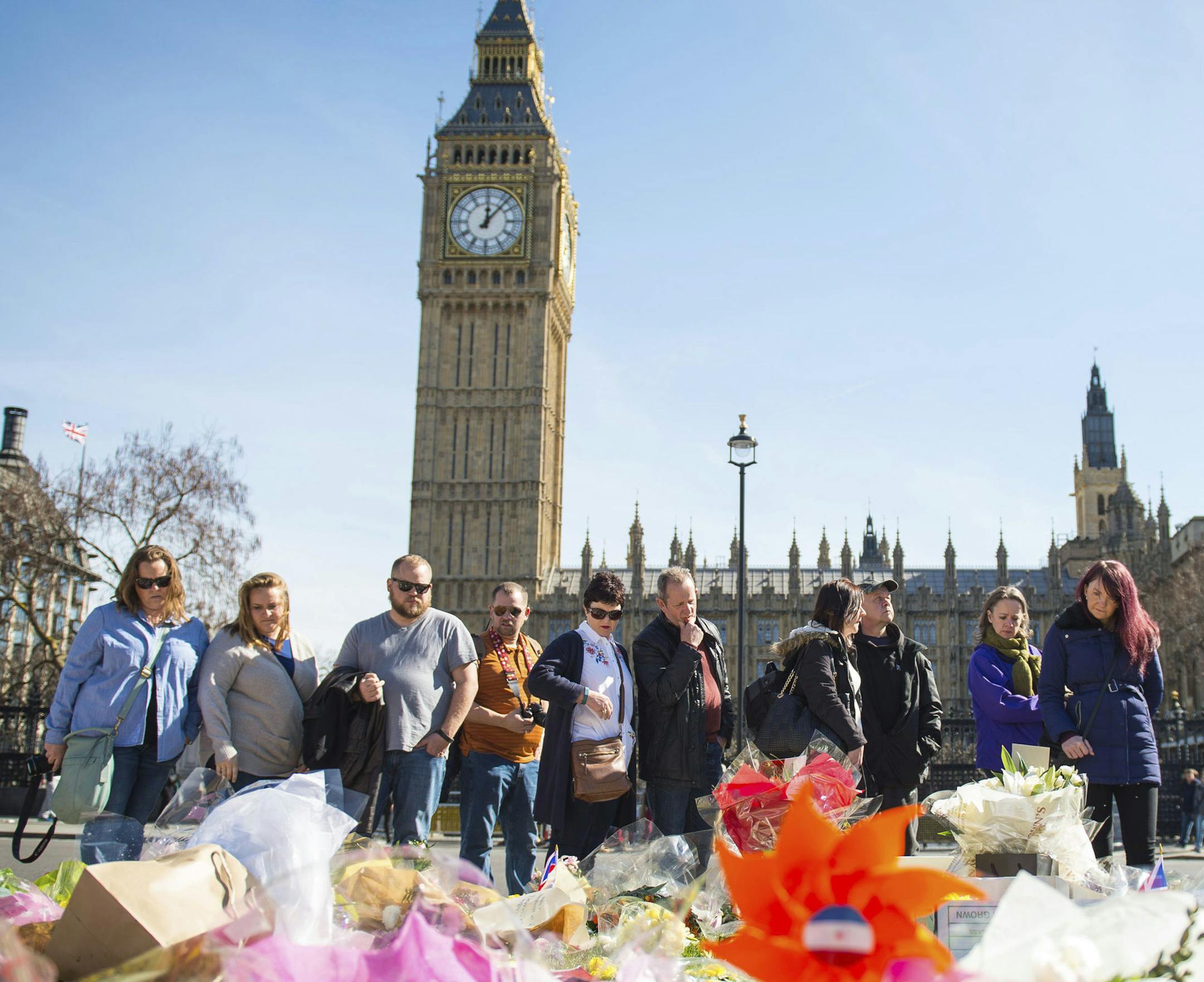 People look at floral tributes in Parliament Square, London, Sunday, March 26, 2017, laid out for the victims of the Westminster attack on Wednesday. Khalid Masood killed four people and left more than two dozen hospitalized, including some with what have been described as catastrophic injuries. The Islamic State group claimed responsibility for the attack. (Dominic Lipinski/PA via AP)
