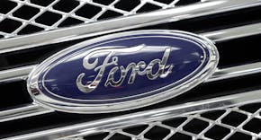 FILE - In this Jan. 5, 2015, file photo, the Ford logo shines on the front grille of a 2014 Ford F-150, on display at a local dealership in Hialeah, F