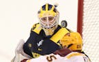 The University of Minnesota's Justin Kloos (25) can't get a rebound shot past University of Michigan goalie Zach Nagelvoort (35) during the second per