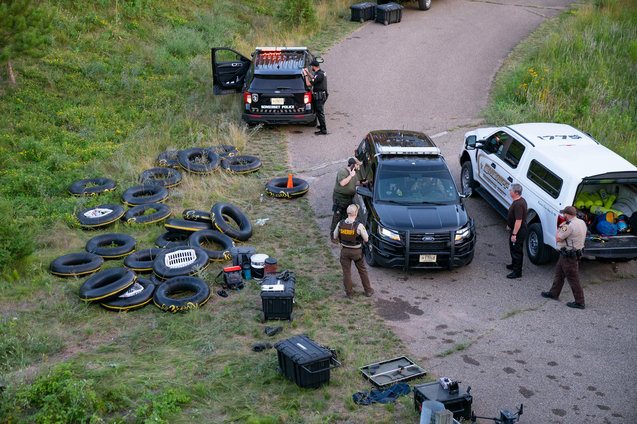 Tubes sit on the bank of the Apple River while Water Recovery authorities comb the area with metal detectors after five people were stabbed while tubing down the river Saturday, July 30, 2022 in Somerset, WI.   ]