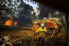 Firefighters protect a house in Conjola, Australia, on Tuesday, Dec. 31, 2019. The country's east coast is dotted with apocalyptic scenes on the last 