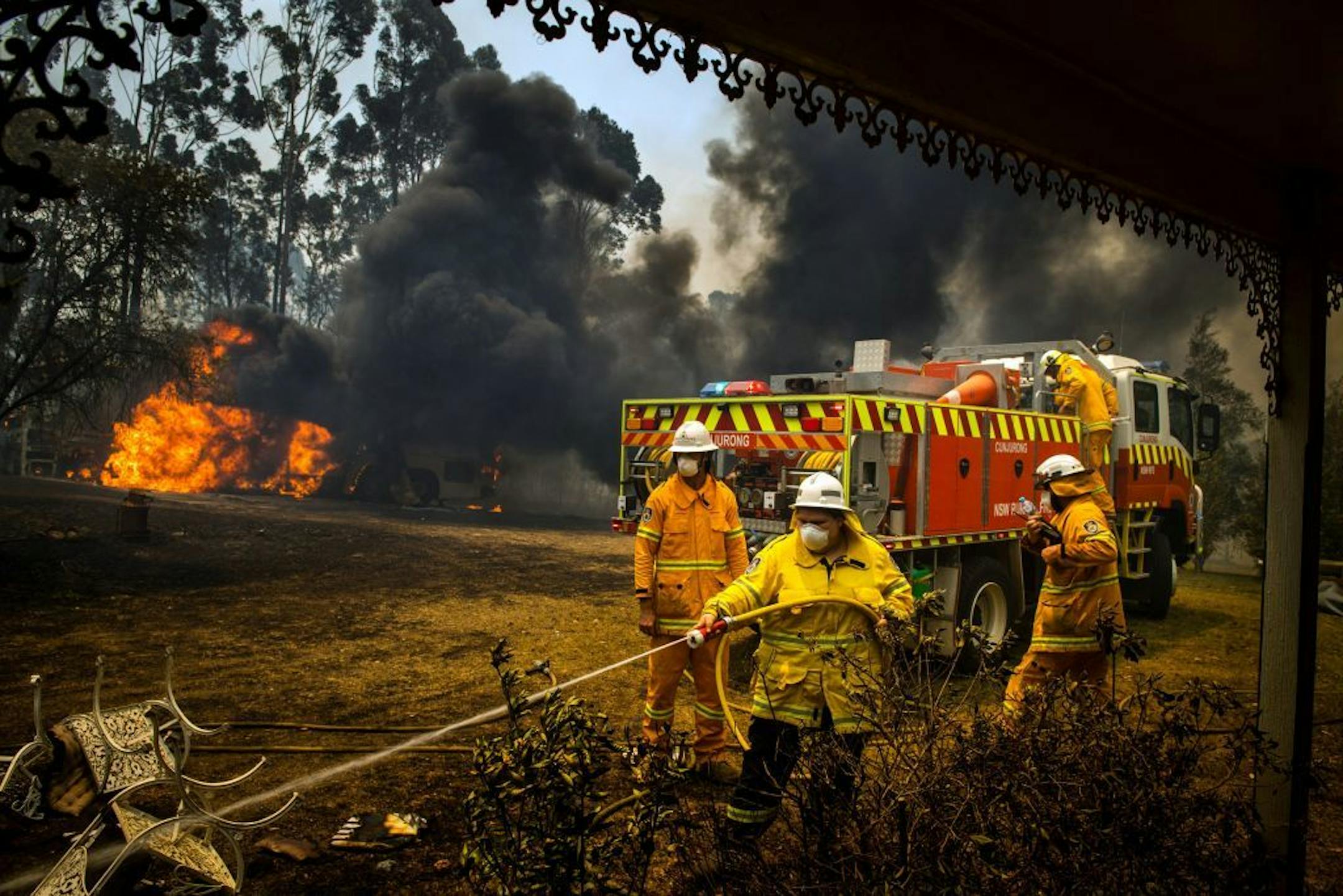 Firefighters protect a house in Conjola, Australia, on Tuesday, Dec. 31, 2019. The country's east coast is dotted with apocalyptic scenes on the last day of the warmest decade on record in Australia.