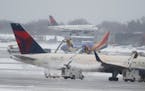 A Delta flight approaches Minneapolis-St. Paul International Airport as another is de-iced, ahead of more snow and sleet Saturday.