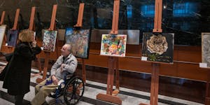 Bill Crane, 60, talks with his guardian Christy Marchand in front of his untitled artwork as part of an "I AM” show on display in the lobby of the U