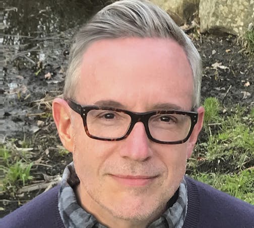 outdoors photo of author Patrick Ryan in a plaid shirt and sweater