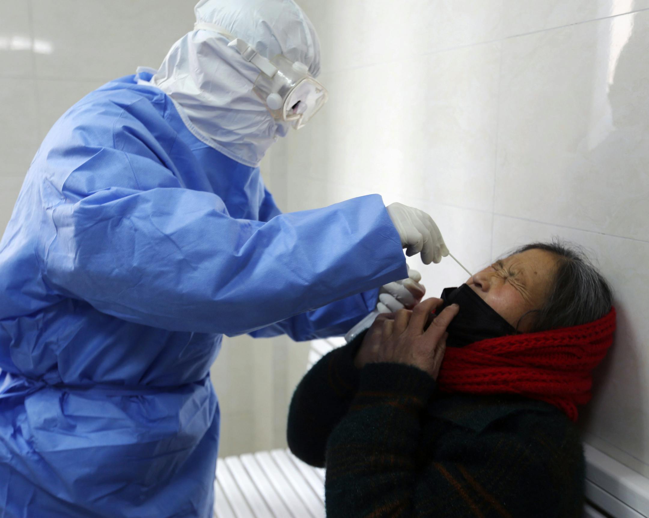 A doctor takes a swab from a woman to test for the COVID-19 virus at a fever clinic in Yinan county in eastern China's Shandong province on Wednesday, Feb. 12, 2020. China on Wednesday reported another drop in the number of new cases of a viral infection and 97 more deaths, pushing the total dead past 1,100 as postal services worldwide said delivery was being affected by the cancellation of many flights to China. (Chinatopix Via AP)