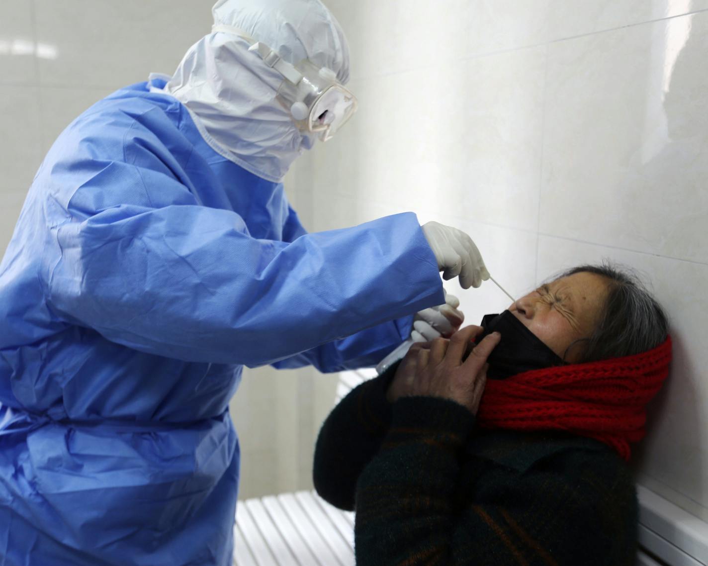 A doctor takes a swab from a woman to test for the COVID-19 virus at a fever clinic in Yinan county in eastern China's Shandong province on Wednesday, Feb. 12, 2020. China on Wednesday reported another drop in the number of new cases of a viral infection and 97 more deaths, pushing the total dead past 1,100 as postal services worldwide said delivery was being affected by the cancellation of many flights to China. (Chinatopix Via AP)