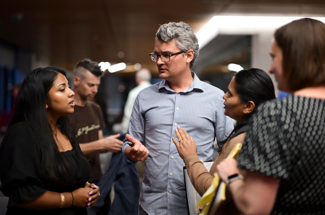 Concerned neighbors of Minnehaha Academy, including Andrew Schmidt, center, and Saumya Verma, speak with Minneapolis City Council Member Aurin Chowdhury, left, after a community meeting Wednesday at Minnehaha Academy.