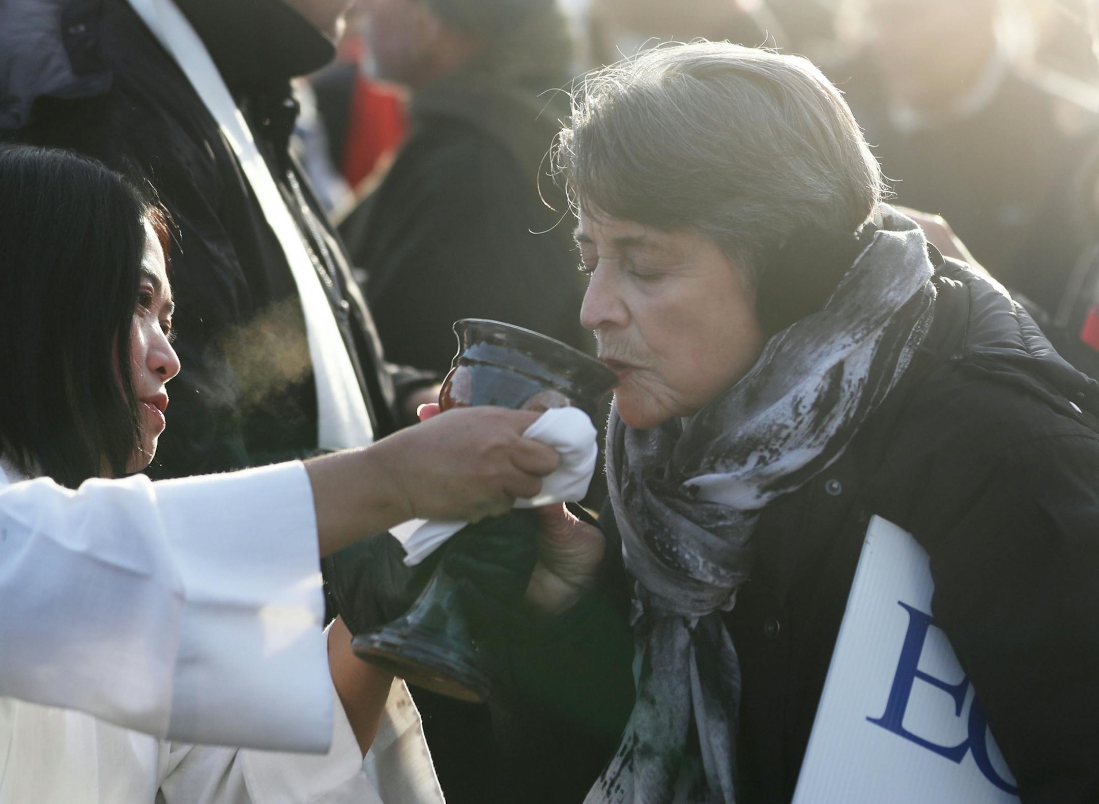 Lay person Hser Moo, left, offered wine during a communion outside the Whipple Federal Building Tuesday, Oct. 29, 2019, in St. Paul, MN. Clergy and protestors gathered for a service and communion outside the Whipple Federal Building and to protest the naming of the building after the Episcopal bishop because deportations and other actions at the courthouse are in opposition to the beliefs of the Episcopal church, they stated.