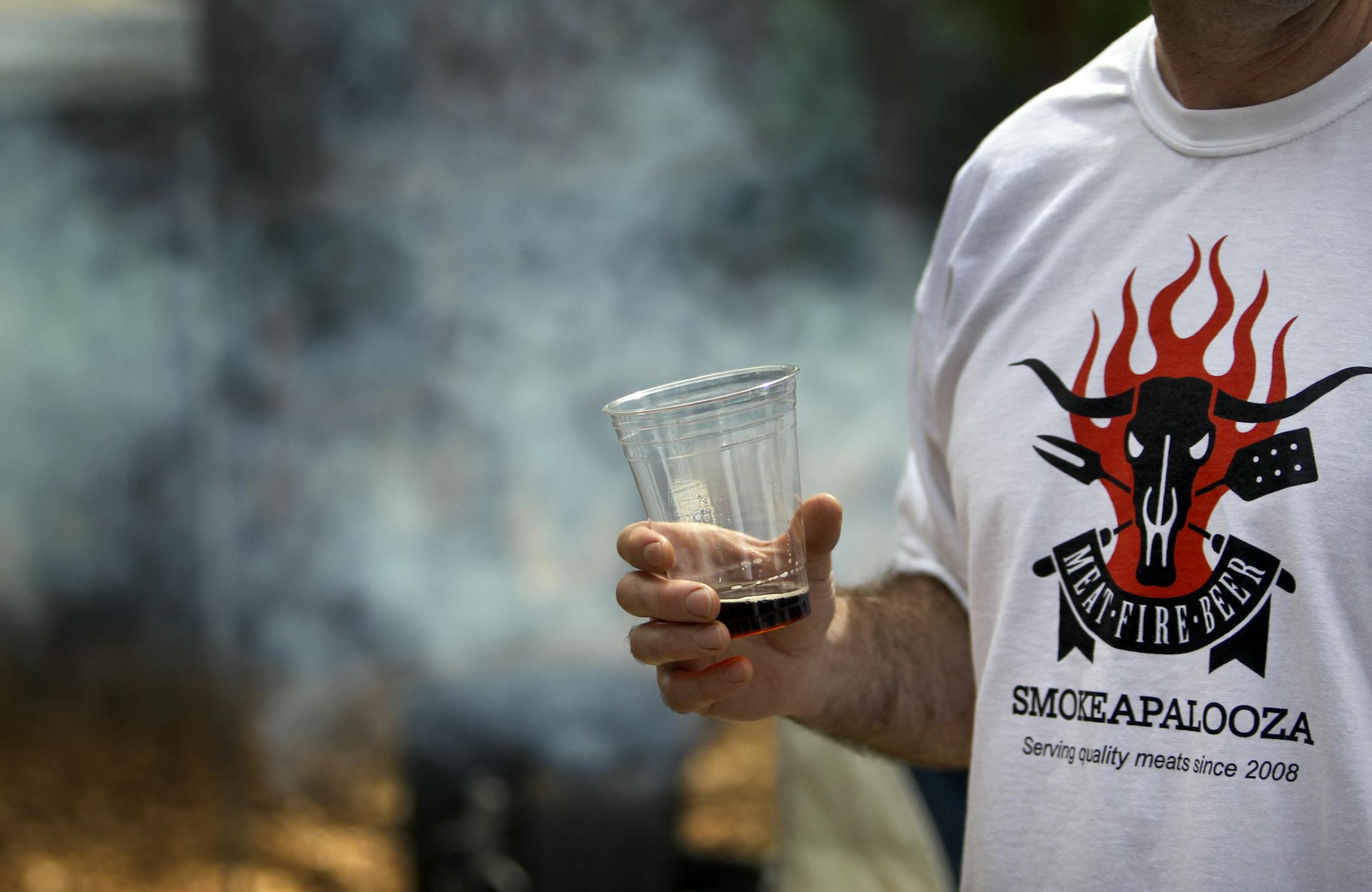 Meat smoking enthusiasted slaked their thirst with smoked porter beer and donned specially made Smokeapolloza T-shirts during Smokapalooza 2013, on the deck of the Pupel family residence Saturday, May 26, 2013 in Plymouth, MN.](DAVID JOLES/STARTRIBUNE) djoles@startribune How do you learn the intricacies and nuances of user a smoker? By having lots and lots of experiments going on at one time. How do you do that? By gathering 10 families, smokers and grills at the ready, for Smokapalooza. Everyon