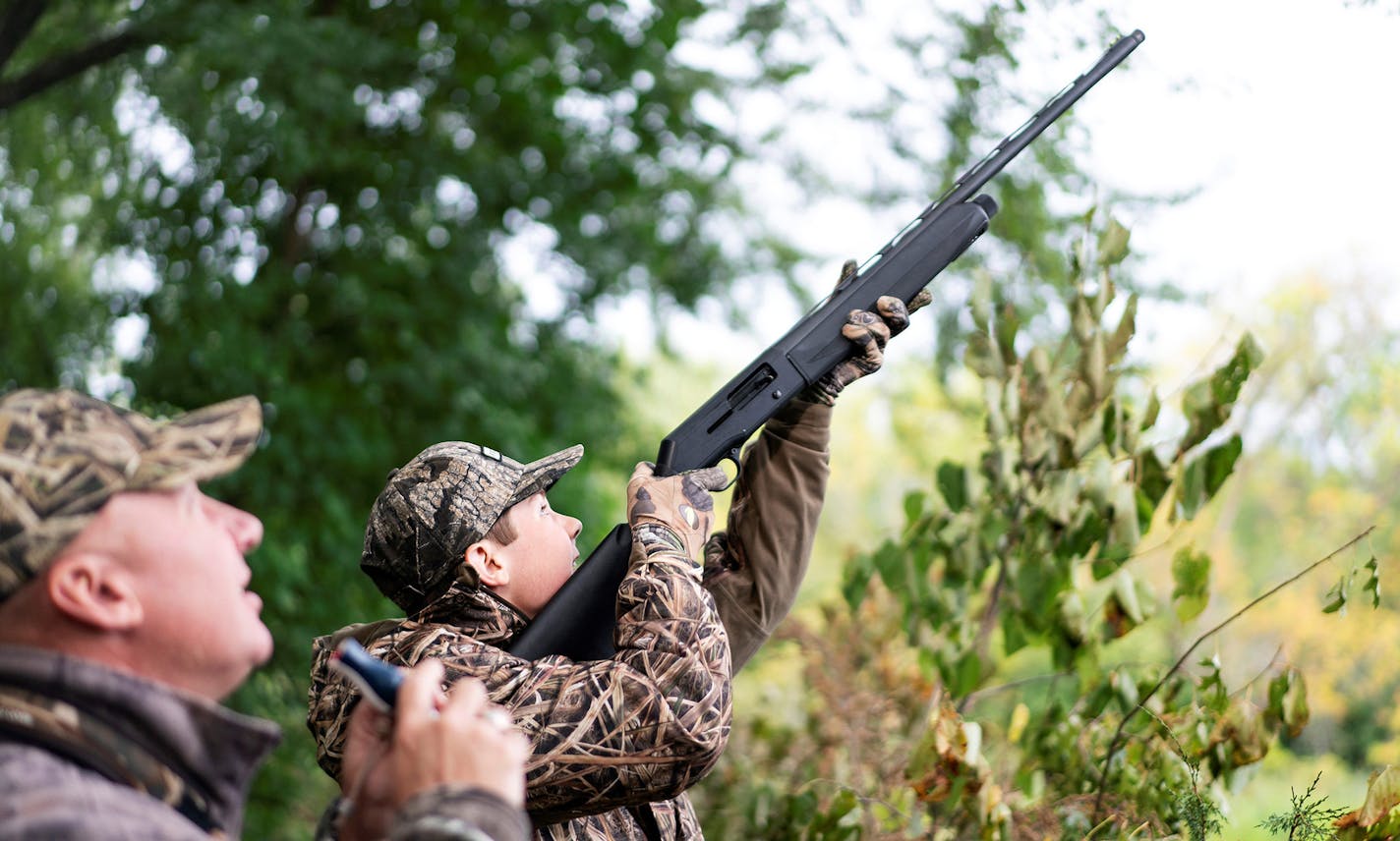 Samuel Nelson, 14, of Sartell takes aim at a duck over the Rum River as his father, Jeff Nelson, 51, a lieutenant colonel in the Minnesota Army National Guard, stands nearby at the Waterfowl for Warriors youth hunt in the Anoka Nature Preserve Saturday September 7, 2019.