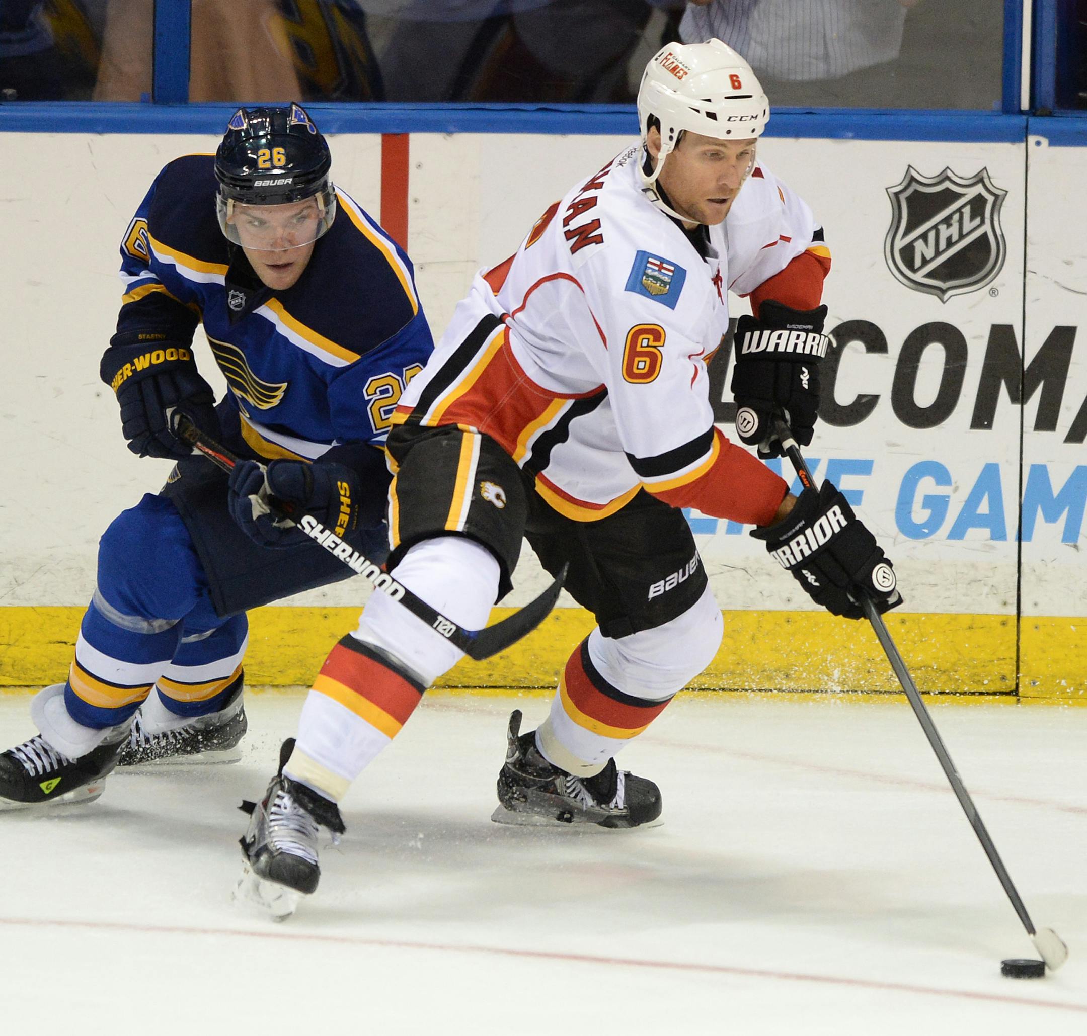 Calgary Flames' Dennis Wideman (6) looks to pass around St. Louis Blues' Paul Stastny (26) during the second period of an NHL hockey game, Saturday, Oct. 11, 2014, in St. Louis. (AP Photo/Bill Boyce)