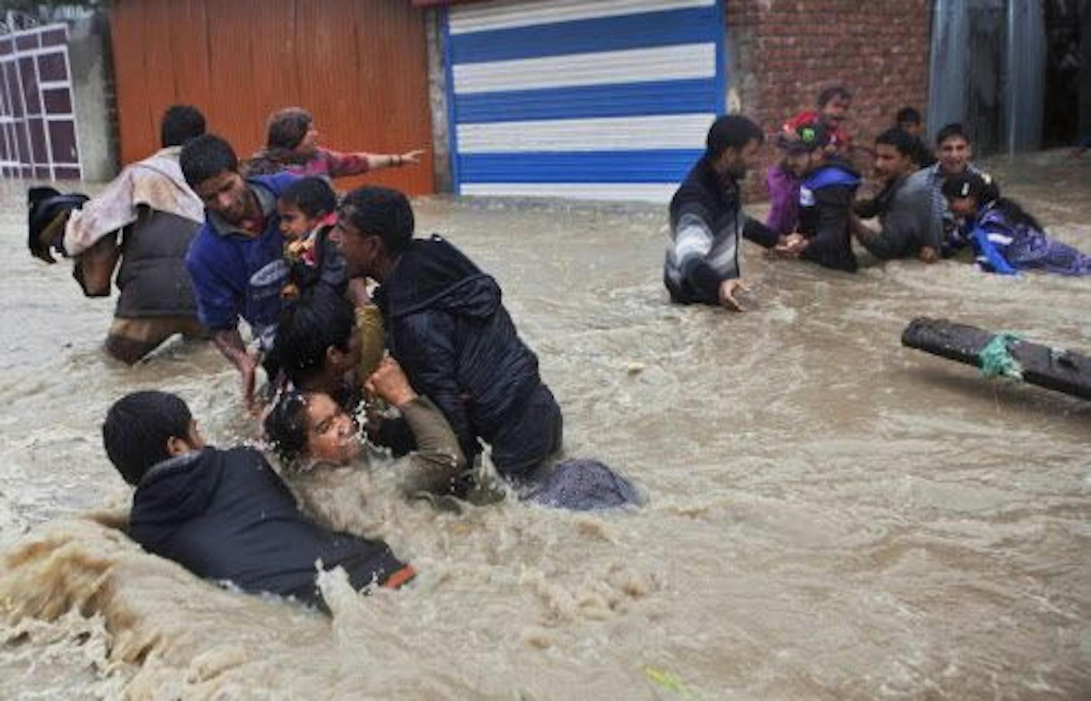 Kashmiri residents struggle to withstand sudden and strong water currents while wading through floodwaters in their efforts to move to safer places in Srinagar, India, Thursday, Sept. 4, 2014.