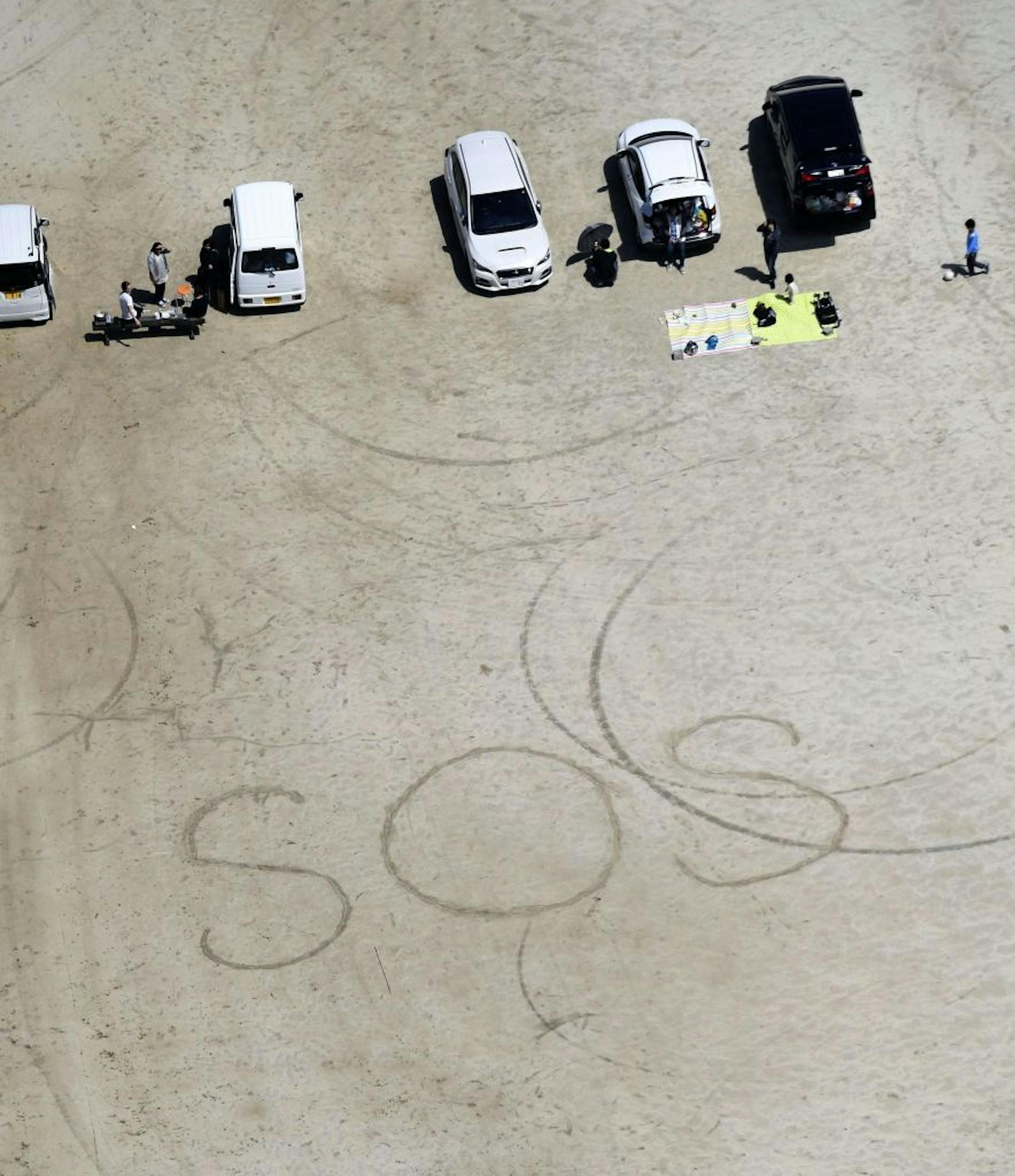 A sign of "SOS'" is written on the ground of an elementary school in Aso, Kumamoto prefecture, southern Japan Saturday, April 16, 2016. Powerful earthquakes a day apart shook southwestern Japan, trapping many others beneath flattened homes and sending thousands of residents to seek refuge in gymnasiums and hotel lobbies. (Muneyuki Tomari/Kyodo News via AP) JAPAN OUT, MANDATORY CREDIT