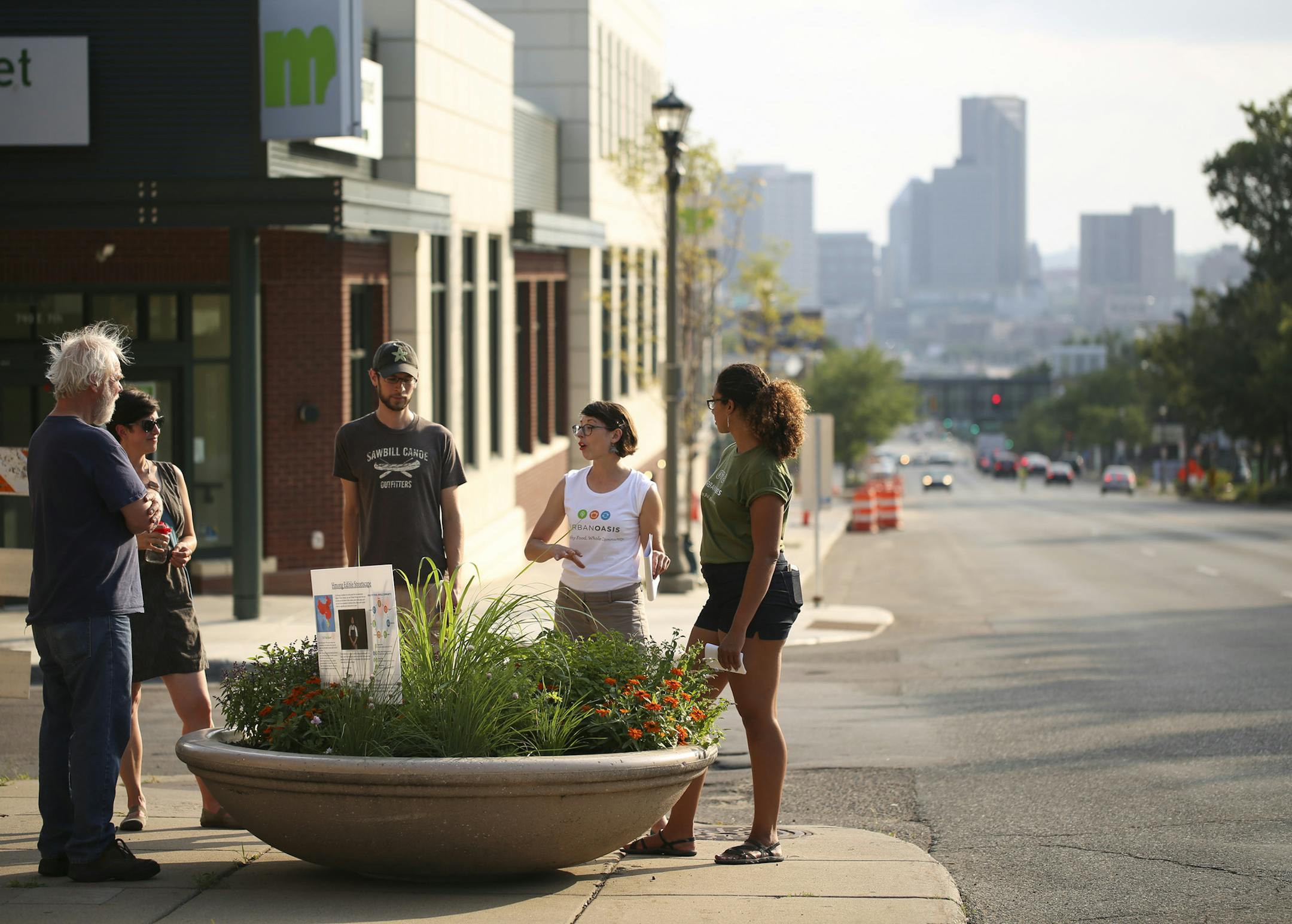 Kim Werst and Miah Ulysse, right, both of Urban Oasis led the tour of the container gardens on E. 7th St. Those on the tour included, from left, Paul Garding, Janelle Nivens, and Matt Frank, who listened as Werst spoke about plants that stem from the Hmong food tradition. ] JEFF WHEELER ï jeff.wheeler@startribune.com Urban Oasis, a sustainable food center, hosted a walking tour of its "Edible Streetscapes" project in St. Paul Wednesday evening, July 20, 2016. A series of ten planters along