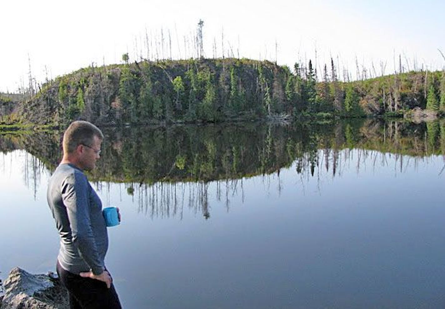 Breakfast was instant oatmeal topped by fresh-picked blueberries or granola with instant milk. Here, Larry Oakes drinks in the view and the last of some instant coffee after the hikers' fourth and last night in the woods, near a babbling brook on the shore of Bingshick Lake.