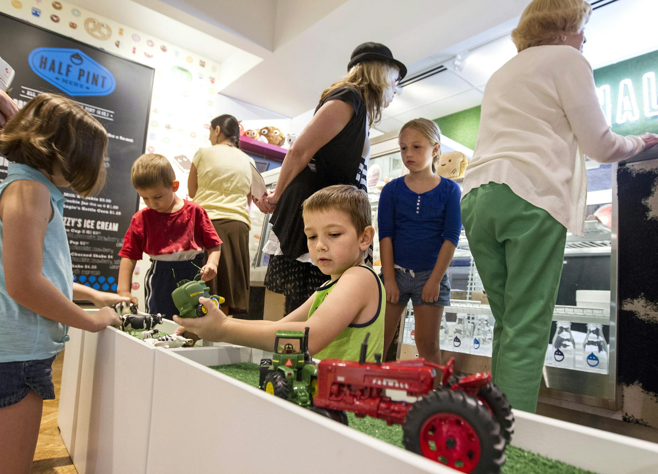 Liam Irwin, 8, center, of Ocala, Florida, plays with cows and tractors with his siblings as his mother looks over the menu at Half Pint in the Minneapolis Institute of Arts July 23, 2014. The kid-focused, locally-sourced eatery aims to show children where food comes from. (Courtney Perry/Special to the Star Tribune)