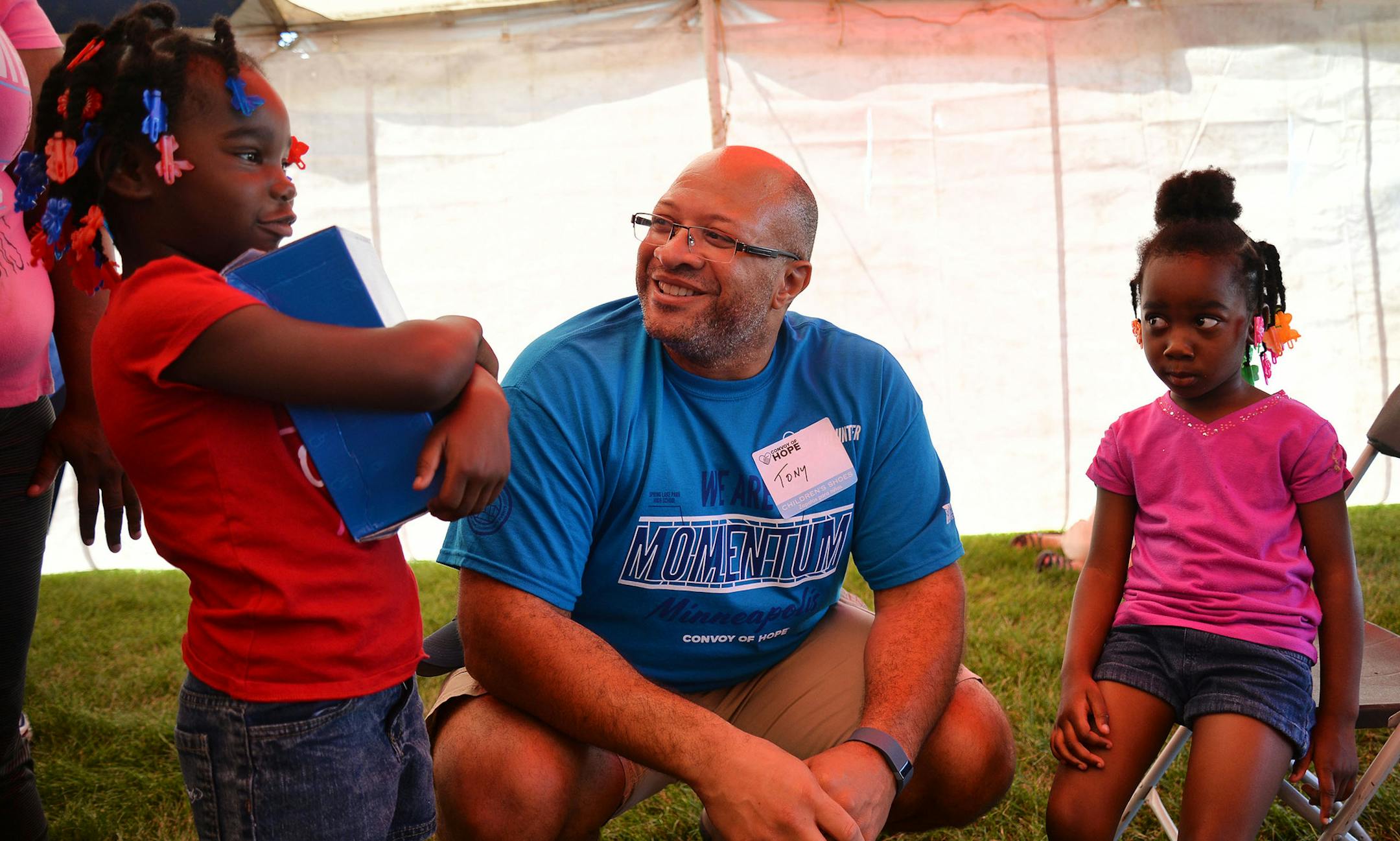 From left, Sintoria Terry, 5, holds her new shoes while talking to Volunteer Tony Easter, of Spring Lake Park, next to Sintoria's sister Diamond Terry, 4, both of Fridley, during Convoy of Hope at Spring Lake Park High School in Spring Lake Park, Minn. on Saturday August 1, 2015. ] RACHEL WOOLF · rachel.woolf@startribune.com Local community volunteers came together to put on Convoy of Hope. The day-long event featured a "kids zone" carnival, various health services, free groceries, shoes an