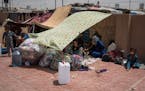FILE - In this Aug. 7, 2016 file photo, women and children rest under an improvised tent in a yard where they have been sleeping at Dibaga camp for in