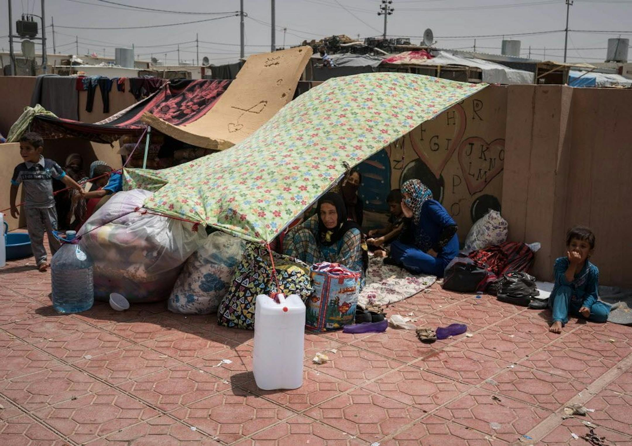 FILE - In this Aug. 7, 2016 file photo, women and children rest under an improvised tent in a yard where they have been sleeping at Dibaga camp for internally displaced civilians in Iraq. The U.N. refugee agency says that more than 100,000 people have been displaced as Iraqi forces clear territory ahead of the critical battle for the Islamic State-held city of Mosul.